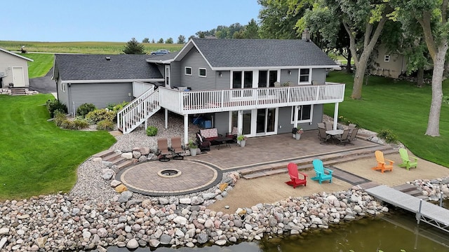 21008 654th Ave, Ellsworth Twp, MN 55355 - rear view of house featuring an outdoor fire pit, roof with shingles, a deck with water view, a patio, and a yard