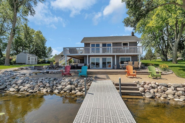 21008 654th Ave, Ellsworth Twp, MN 55355 - rear view of house featuring a deck with water view, a patio area, a fire pit, and a chimney