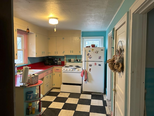 kitchen featuring a textured ceiling, light floors, a wealth of natural light, and white appliances