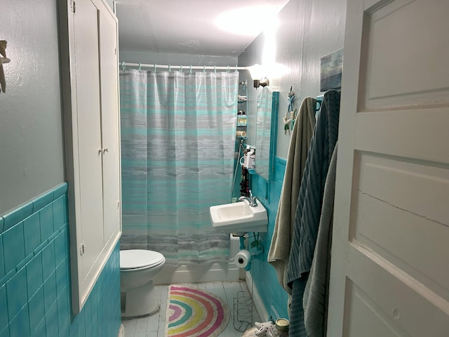 bathroom with toilet, tile walls, wainscoting, and tile patterned flooring