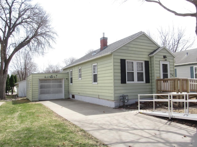 back of house with a wooden deck, a chimney, and concrete driveway
