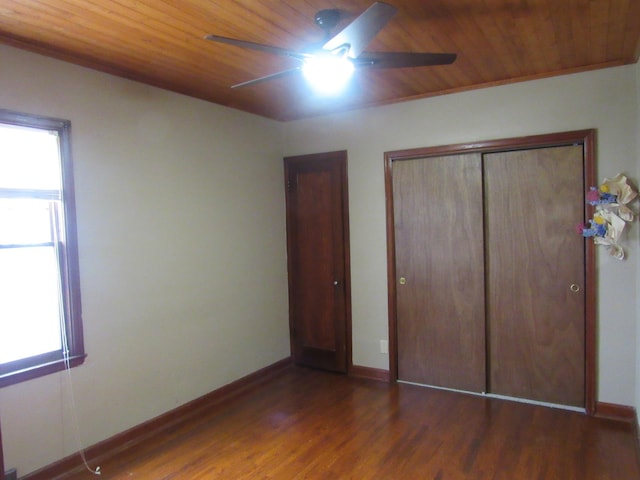 unfurnished bedroom featuring wood finished floors, baseboards, multiple windows, and wooden ceiling