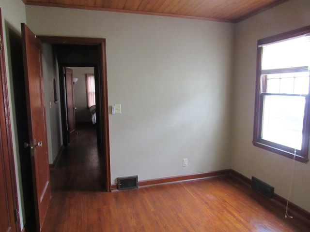 unfurnished room featuring baseboards, wood finished floors, visible vents, and wooden ceiling