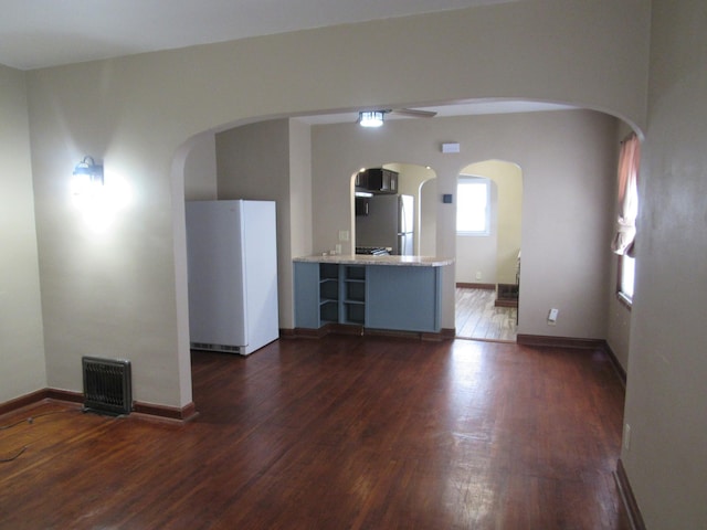interior space featuring arched walkways, dark wood-type flooring, visible vents, and baseboards
