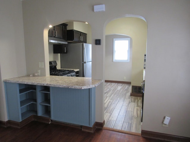 kitchen with range with gas cooktop, baseboards, wood finished floors, light countertops, and under cabinet range hood