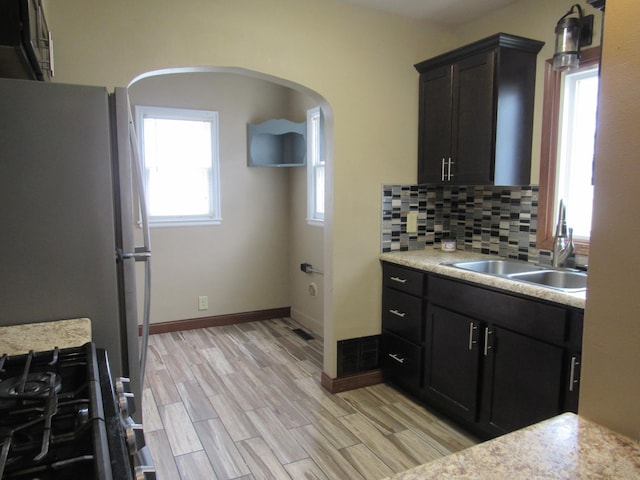 kitchen with gas range, a sink, light countertops, and freestanding refrigerator