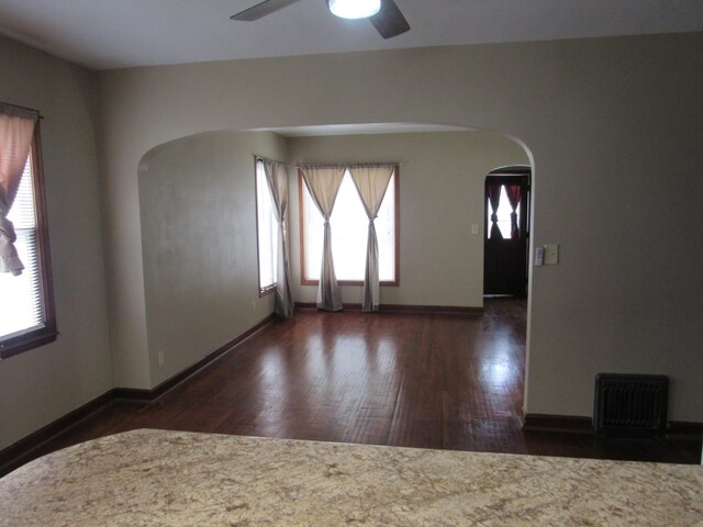 718 Winifred St, Worthington, MN 56187 - unfurnished room featuring wood finished floors, ceiling fan, arched walkways, baseboards, and visible vents