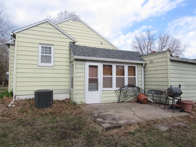 rear view of house with central air condition unit, a patio area, and a shingled roof