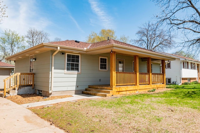 view of front of property with a porch, a front lawn, roof with shingles, and an outbuilding