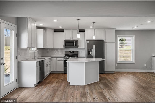 2173 Heron Ct, Lino Lakes, MN 55038 - kitchen featuring a center island, a sink, dark wood finished floors, light countertops, and appliances with stainless steel finishes