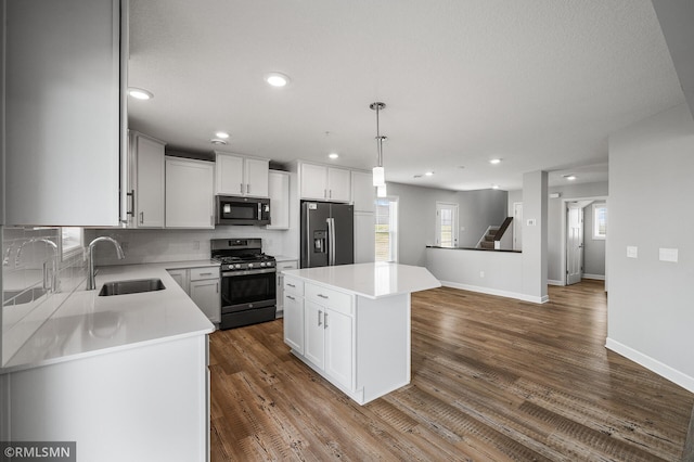 2173 Heron Ct, Lino Lakes, MN 55038 - kitchen featuring stainless steel appliances, a center island, a sink, decorative backsplash, and light countertops