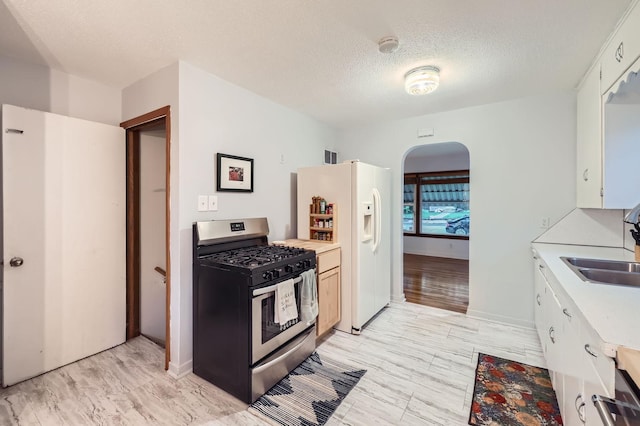 3427 Upton Ave N, Minneapolis, MN 55412 - kitchen with gas stove, white refrigerator with ice dispenser, light countertops, a sink, and arched walkways