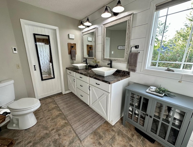 9808 Jenny Ln, Saint Wendel Twp, MN 56374 - full bath featuring double vanity, toilet, a textured ceiling, and baseboards