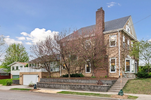 view of front of property with driveway, a garage, and a chimney