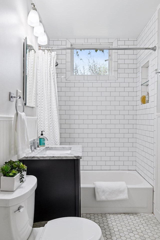 bathroom featuring toilet, shower / bath combo, tile patterned floors, vanity, and wainscoting