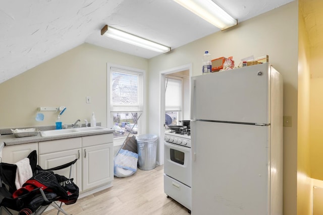 850 22nd Ave SE, Minneapolis, MN 55414 - kitchen featuring light wood-style flooring, a sink, vaulted ceiling, white cabinetry, and white appliances