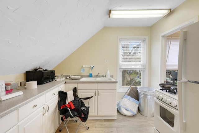 850 22nd Ave SE, Minneapolis, MN 55414 - kitchen featuring light wood finished floors, vaulted ceiling, a sink, white appliances, and white cabinetry