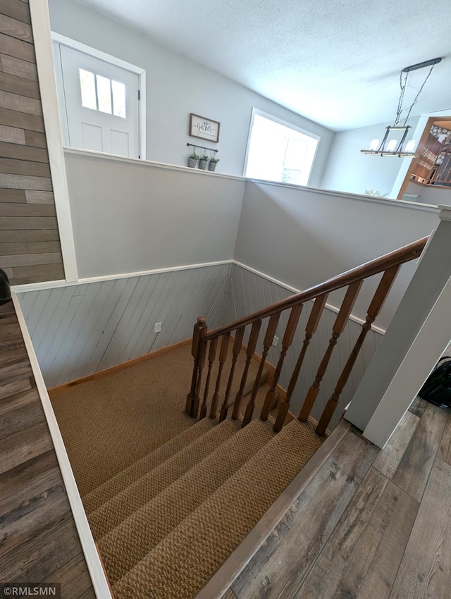 32255 County 21, Browerville, MN 56438 - staircase featuring wood finished floors, a wainscoted wall, wood walls, and a chandelier