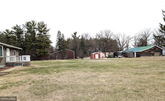 32255 County 21, Browerville, MN 56438 - view of grassy yard featuring a shed, an outdoor structure, a wooden deck, a garage, and view of scattered trees