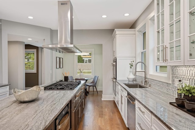 1647 26th St, Minneapolis, MN 55405 - kitchen with a sink, island range hood, appliances with stainless steel finishes, white cabinetry, and light stone countertops