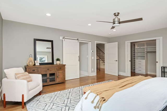 1647 26th St, Minneapolis, MN 55405 - bedroom featuring a barn door, wood finished floors, baseboards, a ceiling fan, and a closet