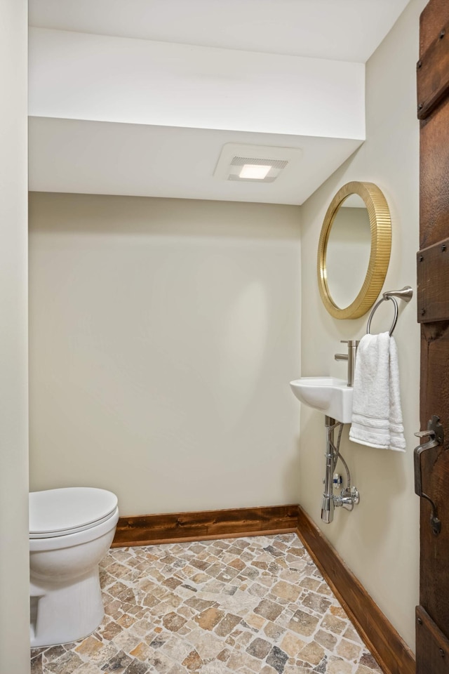 1647 26th St, Minneapolis, MN 55405 - bathroom with baseboards, stone finish flooring, and toilet