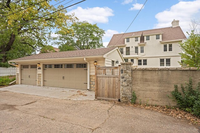 1647 26th St, Minneapolis, MN 55405 - view of property exterior with fence, stone siding, a gate, a chimney, and driveway