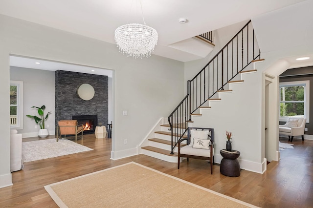 1647 26th St, Minneapolis, MN 55405 - foyer entrance with stairs, wood finished floors, a chandelier, a stone fireplace, and baseboards