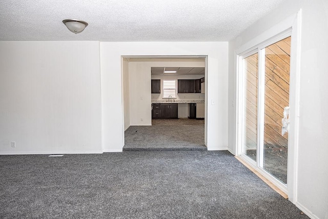 empty room featuring baseboards, a sink, dark carpet, and a textured ceiling
