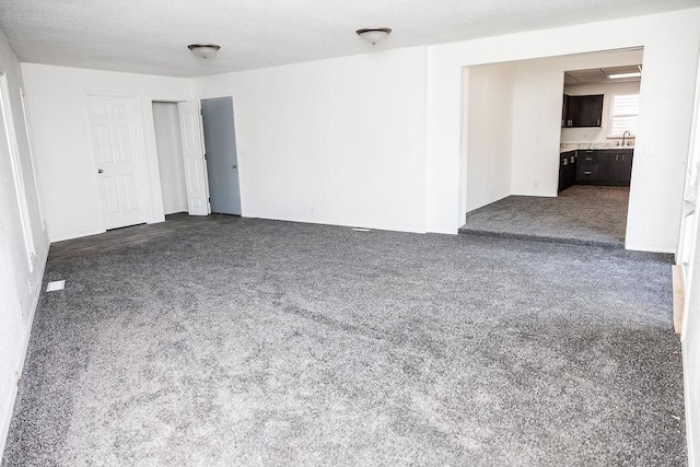 unfurnished room featuring dark colored carpet and a sink