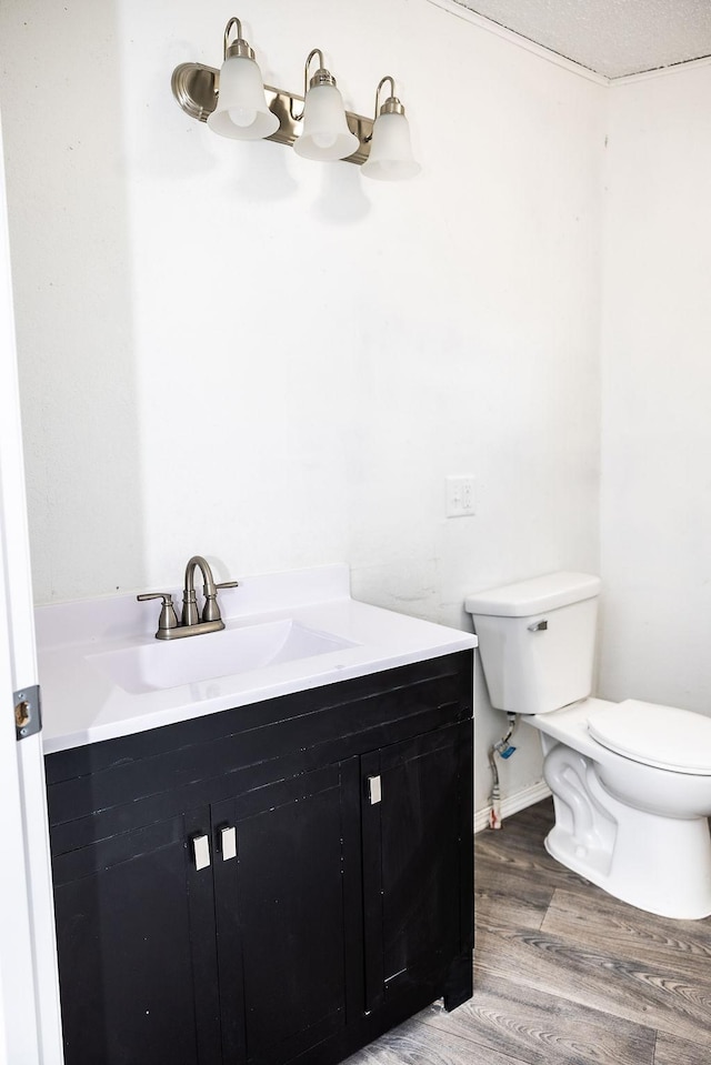 bathroom featuring baseboards, wood finished floors, toilet, and vanity