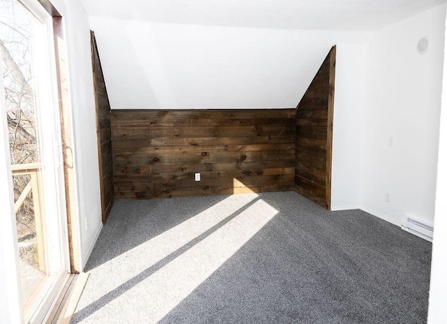 bonus room with a baseboard heating unit, carpet flooring, and wooden walls