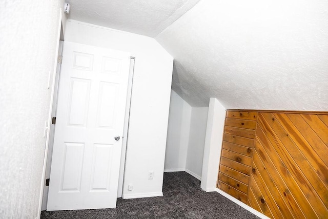 bonus room with lofted ceiling, wood walls, carpet flooring, and baseboards