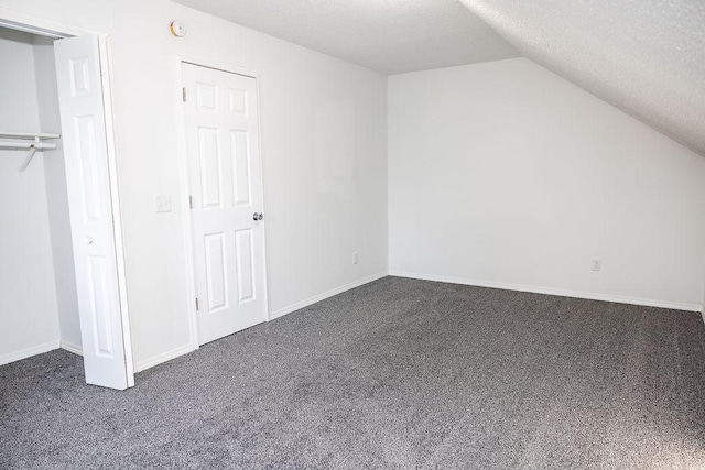 bonus room with vaulted ceiling, dark colored carpet, a textured ceiling, and baseboards