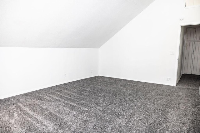 bonus room with vaulted ceiling, baseboards, and dark colored carpet