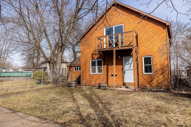 back of property with a lawn, fence, a balcony, and entry steps