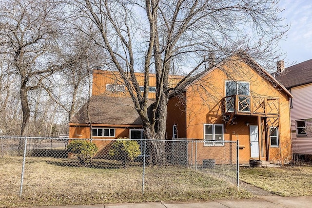 view of front facade featuring stucco siding, a balcony, and a fenced front yard