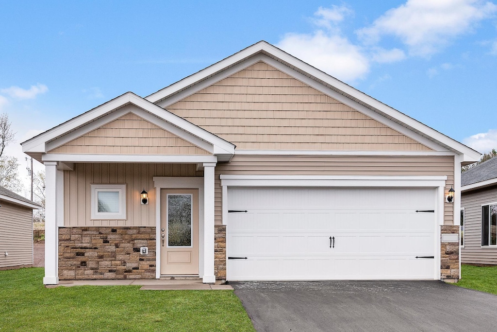 view of front of property with an attached garage, aphalt driveway, stone siding, and board and batten siding