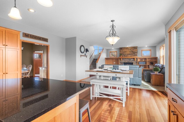 17639 Heidelberg Way, Lakeville, MN 55044 - kitchen featuring light wood-type flooring, a fireplace, hanging light fixtures, dark stone countertops, and recessed lighting