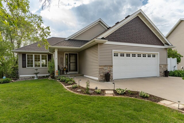 craftsman-style house with driveway, a garage, a front lawn, stone siding, and roof with shingles
