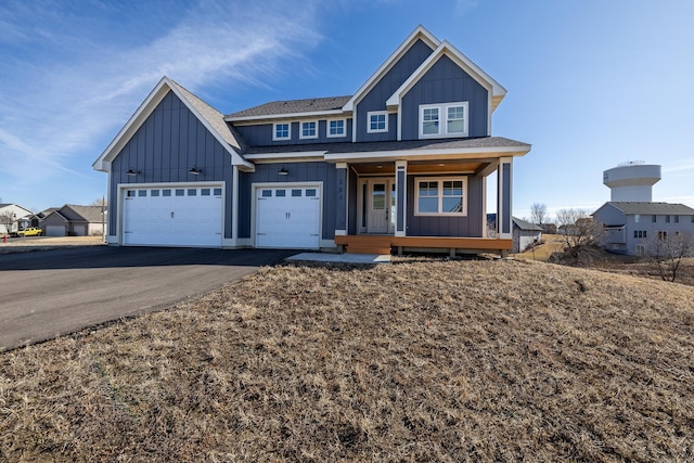 4240 Inland Ln N, Plymouth, MN 55446 - view of front of house featuring aphalt driveway, a garage, board and batten siding, and covered porch