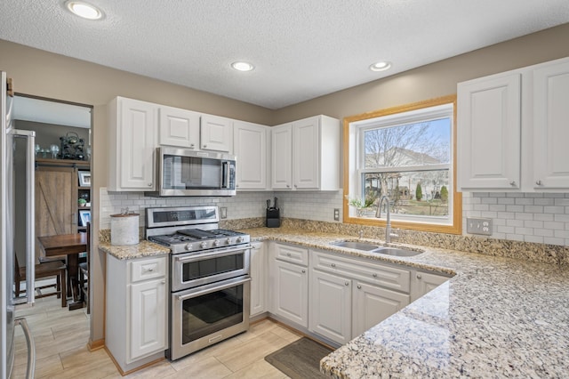 104 Birch Ave NW, Saint Michael, MN 55376 - kitchen with appliances with stainless steel finishes, a sink, white cabinetry, backsplash, and a textured ceiling
