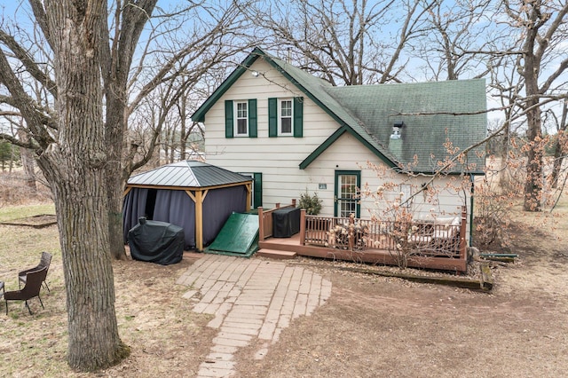 back of house featuring a wooden deck, a gazebo, and a shingled roof