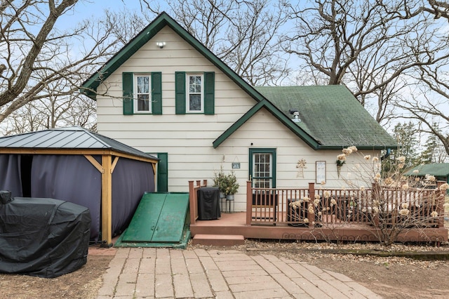 back of house with a wooden deck, a gazebo, and a shingled roof