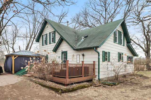 back of property featuring a wooden deck and roof with shingles