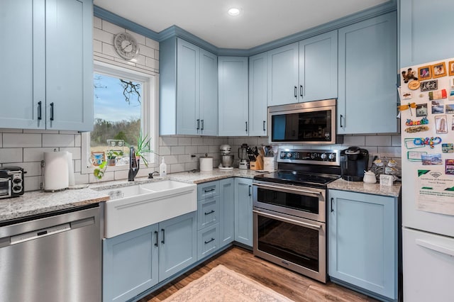 kitchen with blue cabinetry, appliances with stainless steel finishes, tasteful backsplash, and a sink