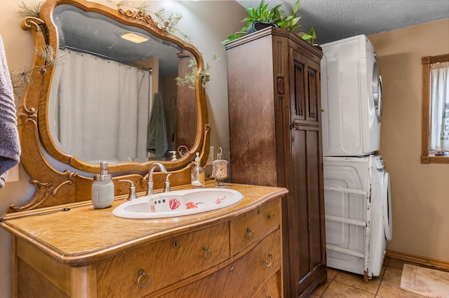 bathroom featuring stacked washer and dryer, tile patterned flooring, and vanity