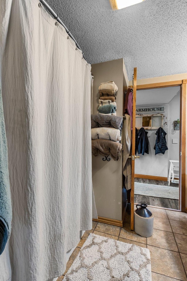 interior space with tile patterned floors, a shower with curtain, and a textured ceiling