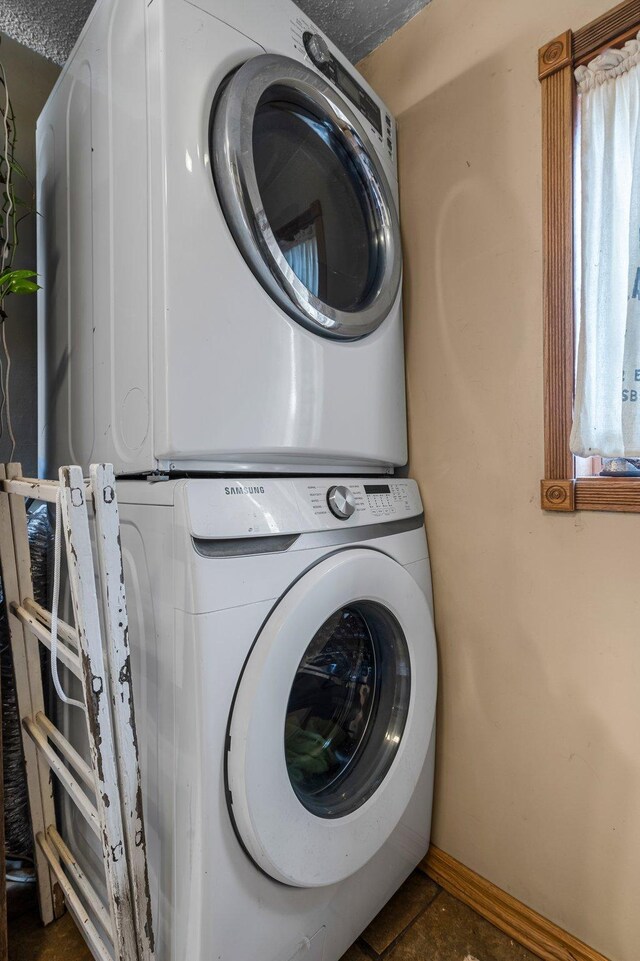 clothes washing area with stacked washing maching and dryer, baseboards, and laundry area