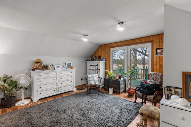 sitting room featuring ceiling fan, lofted ceiling, wood finished floors, and wooden walls